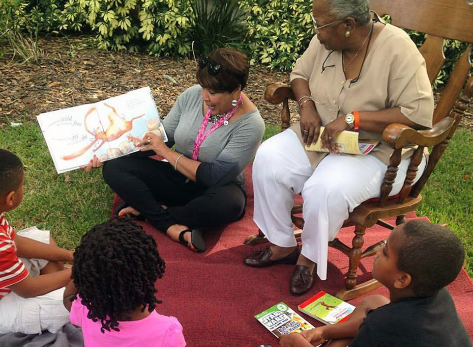Photo of Terri Lipsey Scott reading to kids outside.